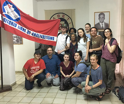Students of Modern Latin American History learn about the Cuban Literacy Campaign and pose with an anti-literacy banner and the museum director in Havana.