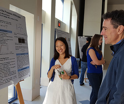 A physics student with her presentation board at the Science Research Symposium.
