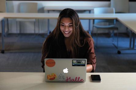 Image of Halle Paredes ’21 smiling and working at a computer