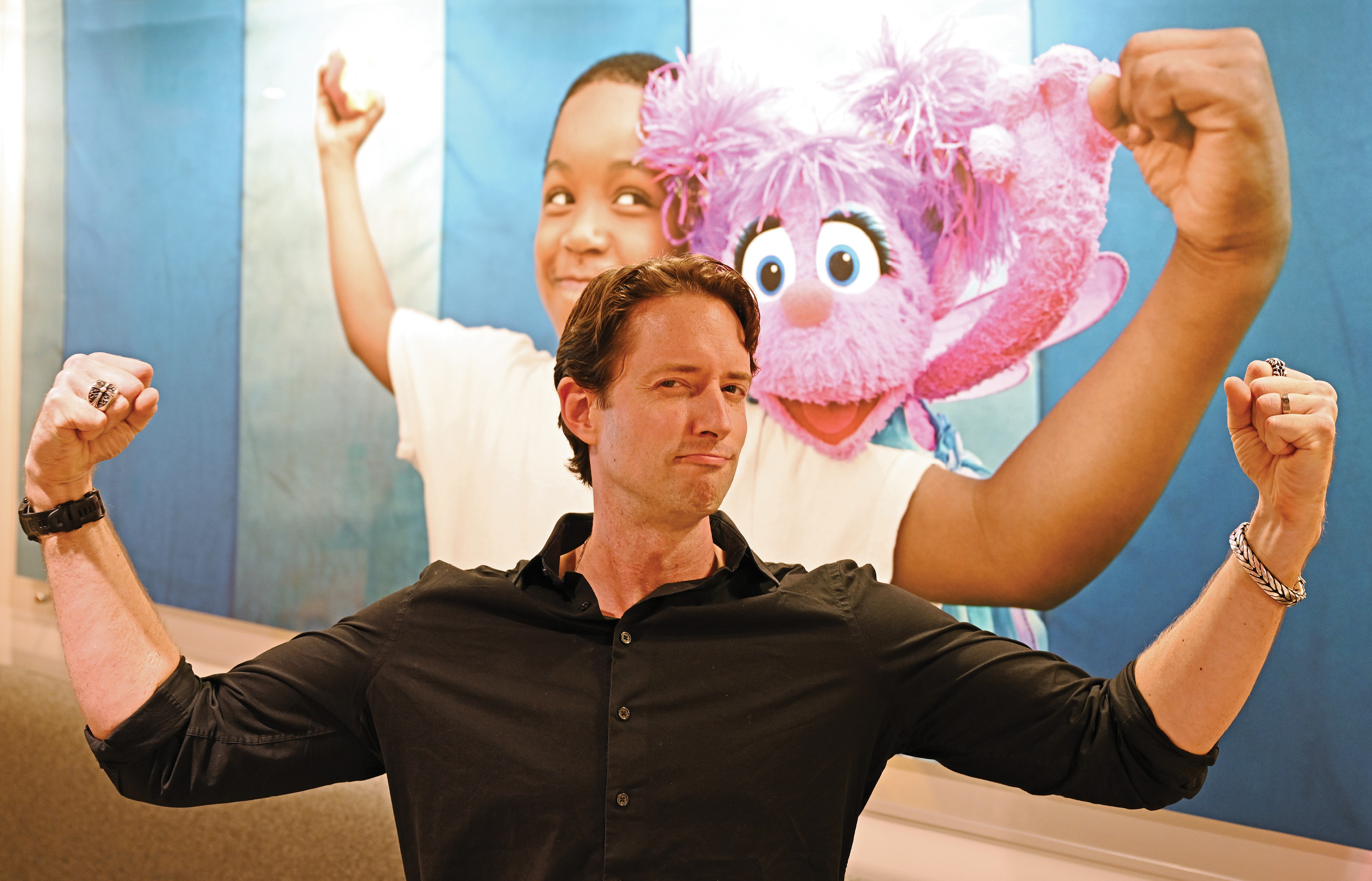 Image of TV producer Jordan Geary '04 in front of a large Sesame Street mural
