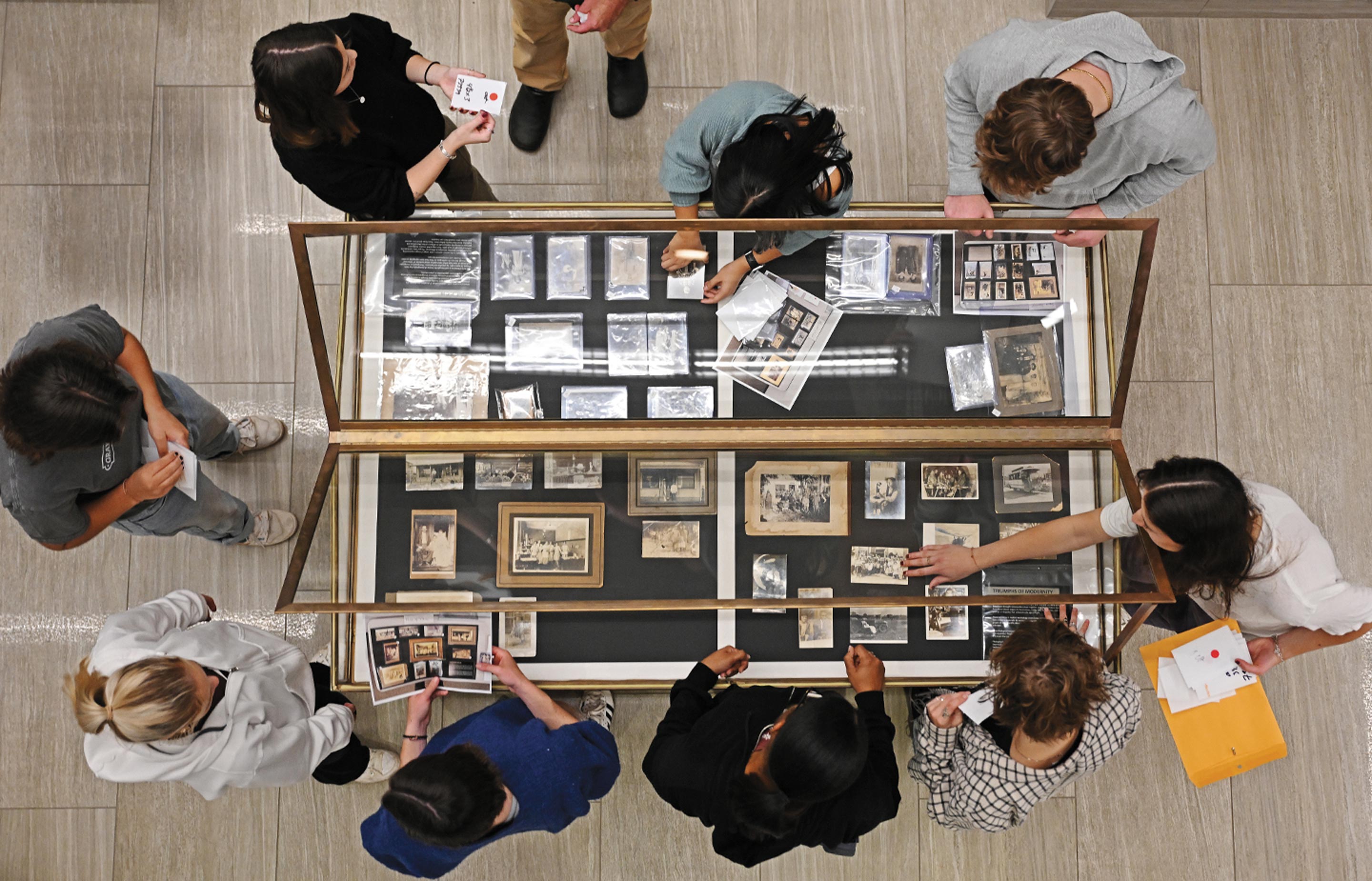 Overhead image of students loading photographs into a display case
