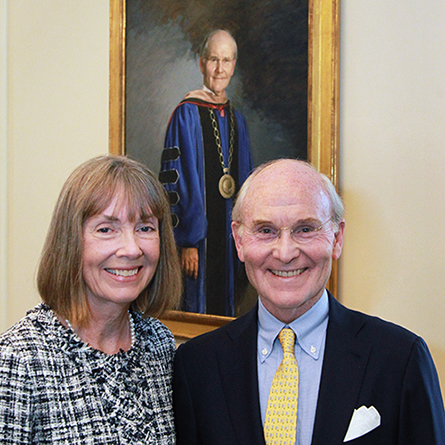 Ann Higdon and President Emeritus Leo I. Higdon Jr. in front of Higdon's official portrait in the Ernst Common Room of Blaustein Humanities Center