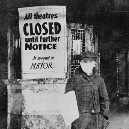 A child in a mask stands next to a sign that announces theaters are closed due to the 1918 flu pandemic.