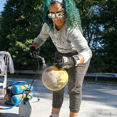 Professor Maria Rosa sprays sugar water on a tetherball that will be used to create a void in a reef ball. 
