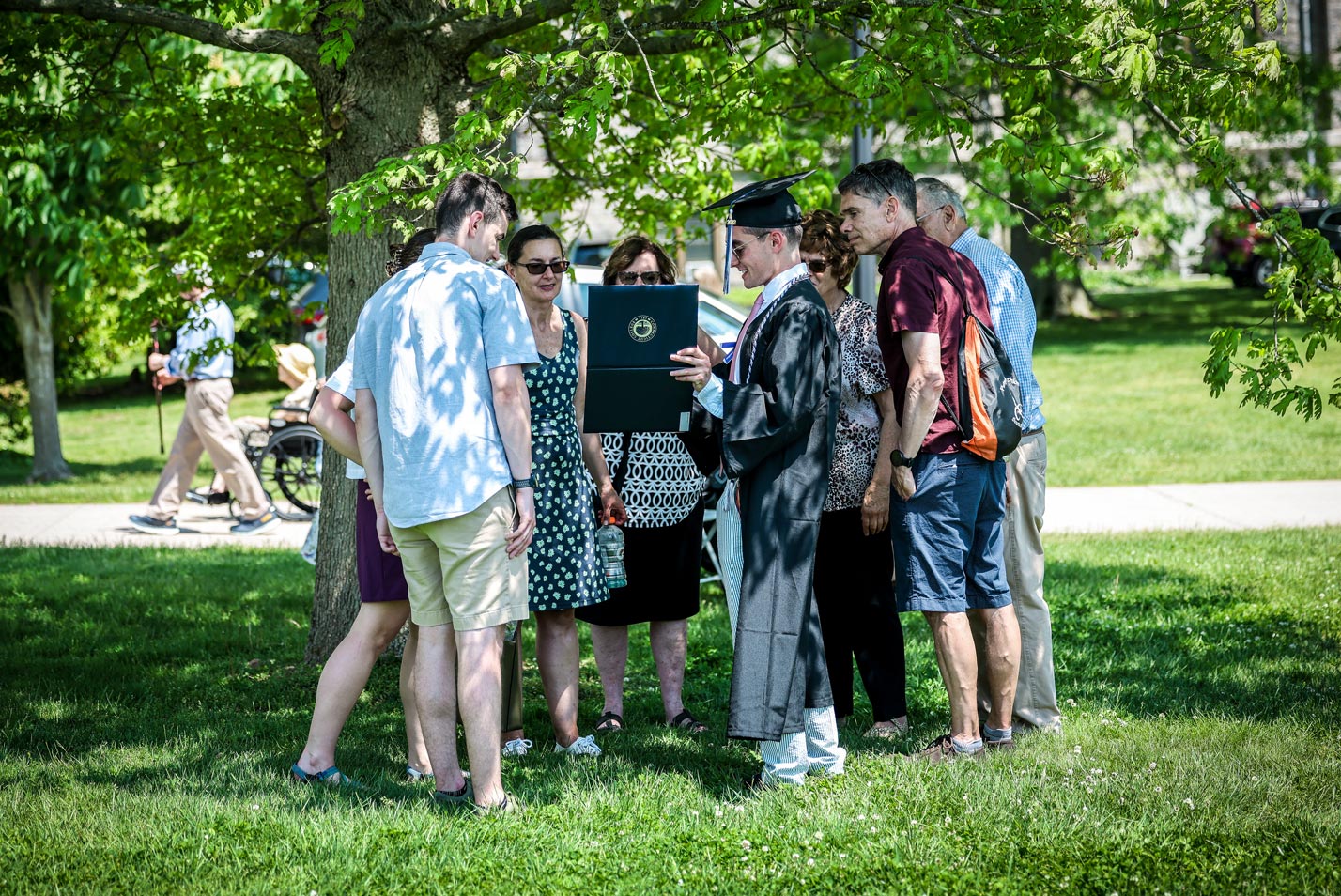 A graduate shows his diploma to family and friends