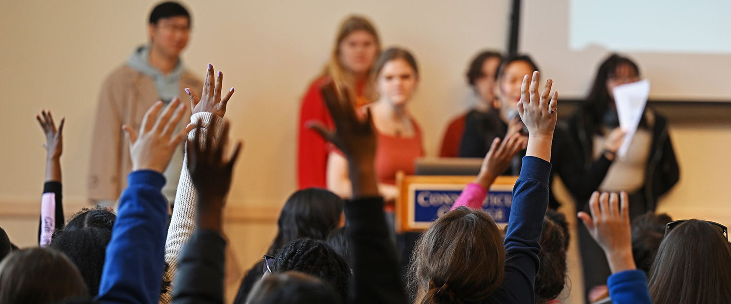Fifth graders raise their hands to answer a question posed by Conn students.