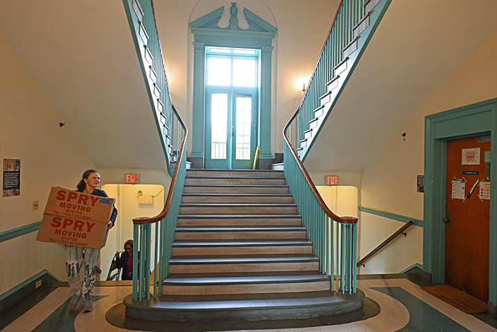A student carries a box up a historic staircase in one of Conn's residence halls.