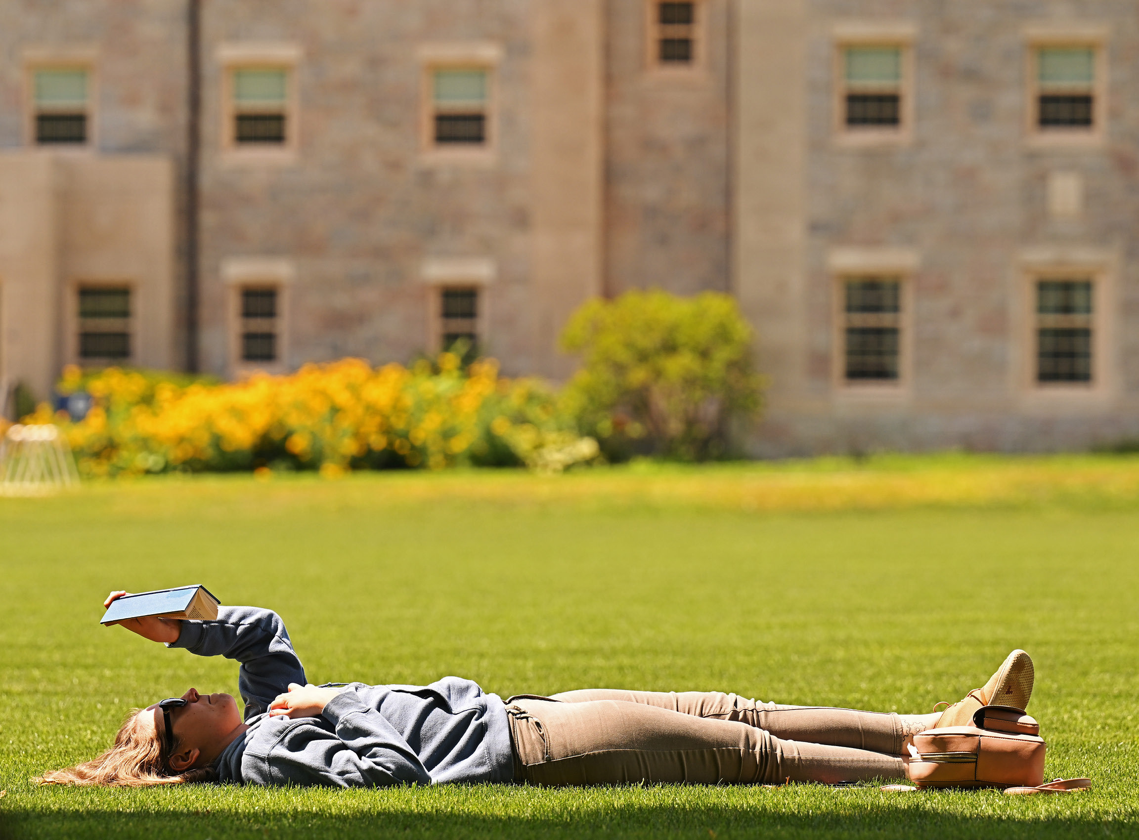 A student lies on the Green reading a book.