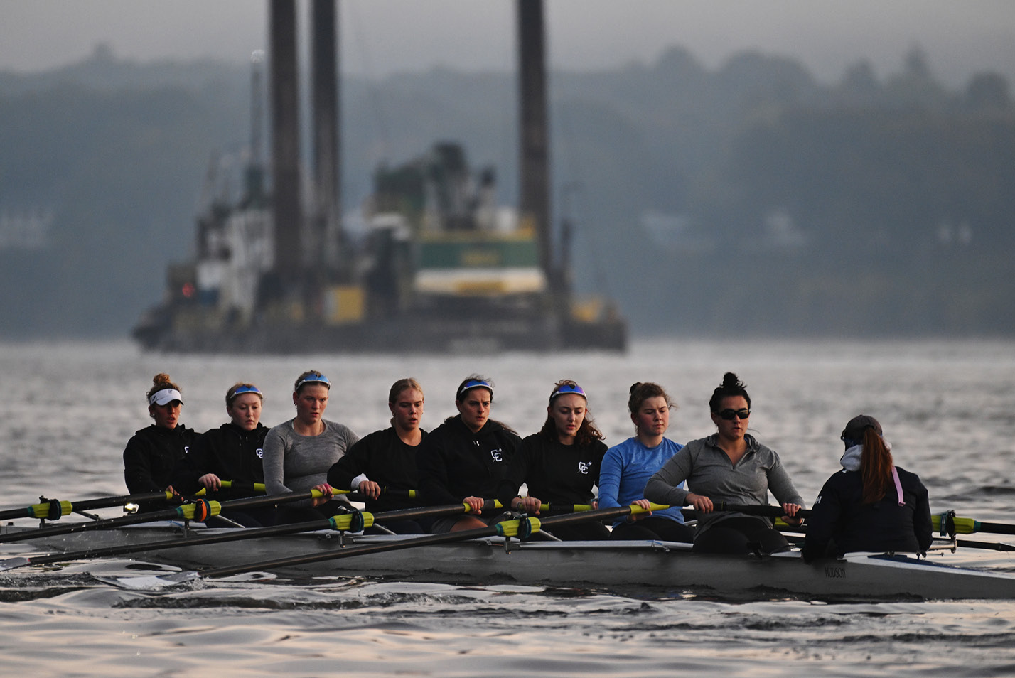 Womens crew rows on the Thames River at dawn in October.
