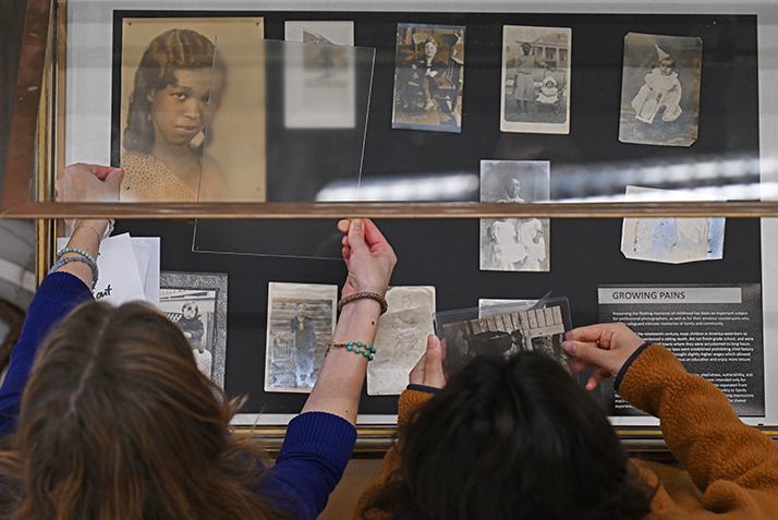 Students arrange photographs in the display case