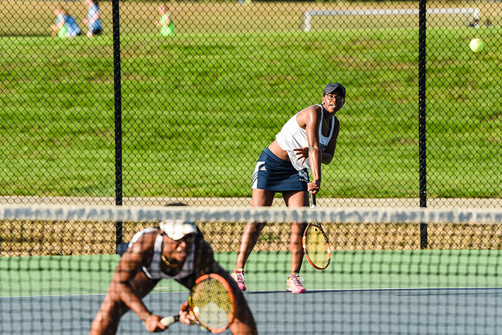 Students play doubles tennis.