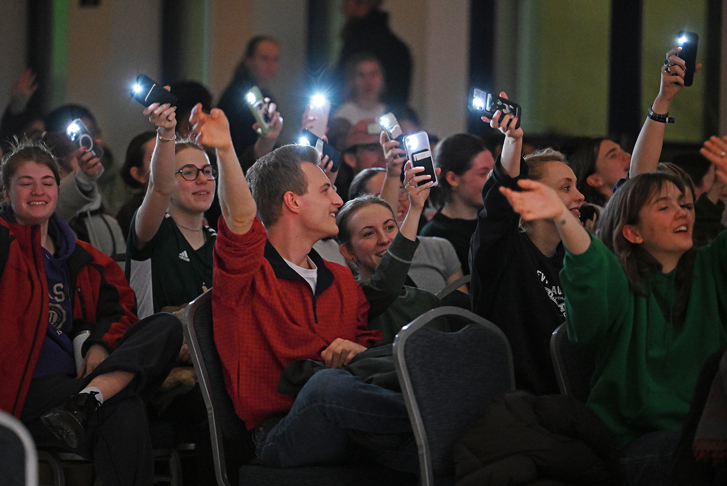Crowd of students waving camera phone flashlights.