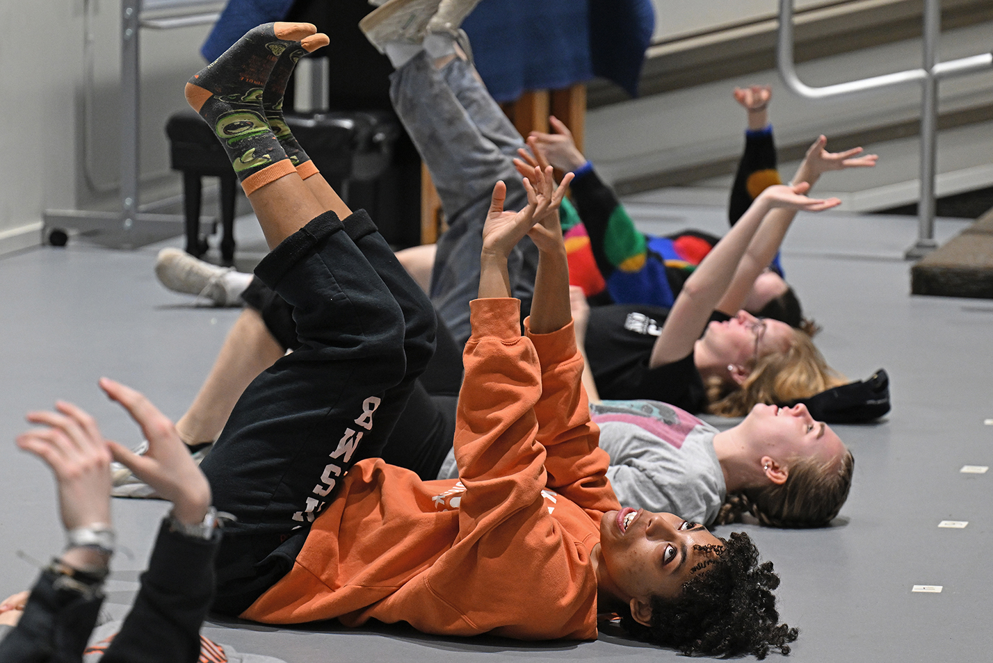 actors lay on floor with hands and feet in the air