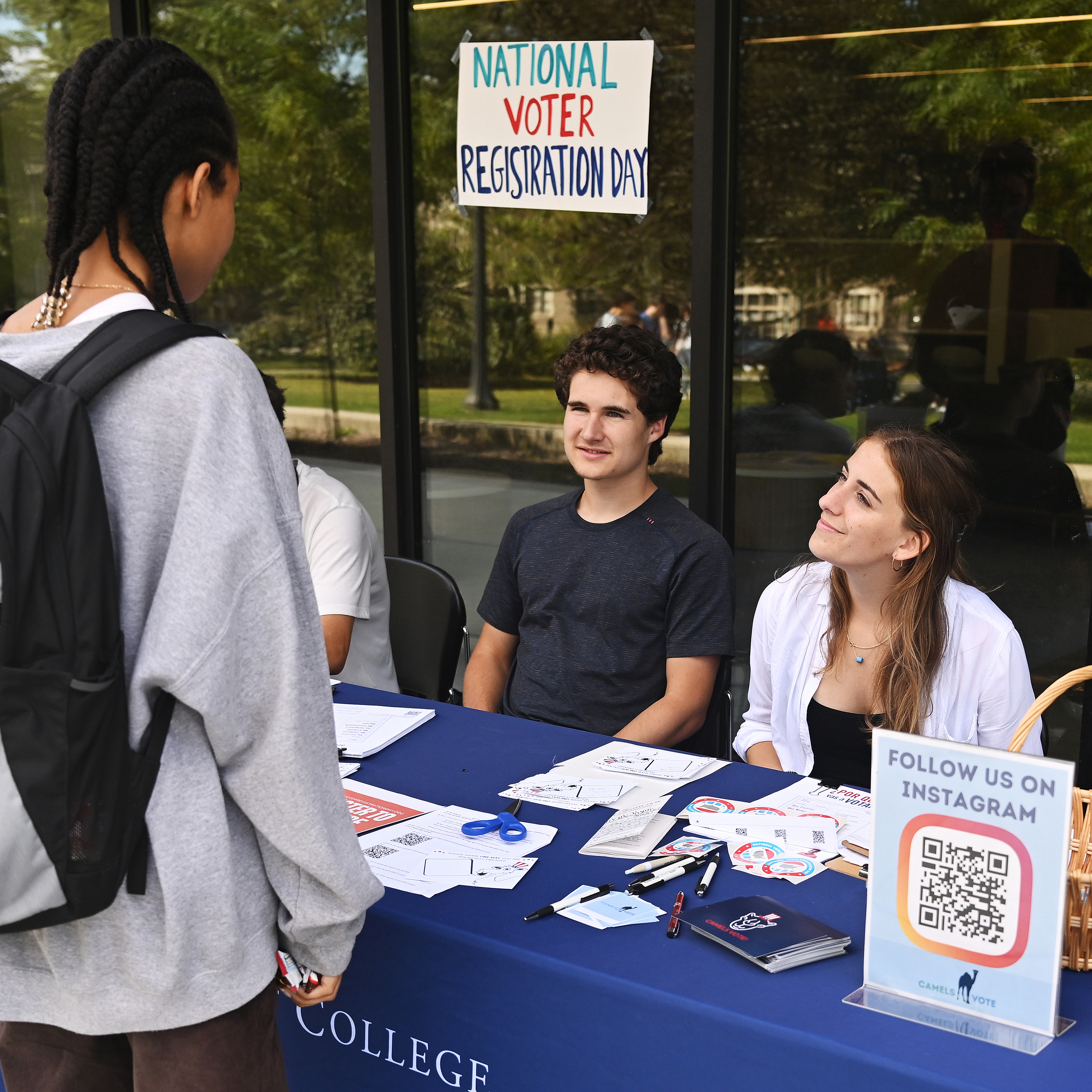 Two students seated at a table run a voter registration drive.