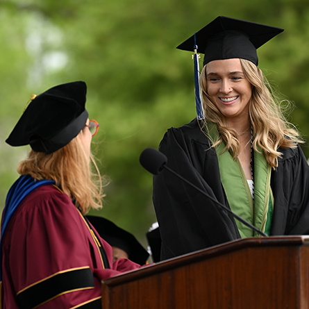 Sarah Hall ’24 smiles at Dean of the Faculty R. Danielle Egan after being awarded the 2024 Claire Gaudiani ’66 Prize at Commencement. 