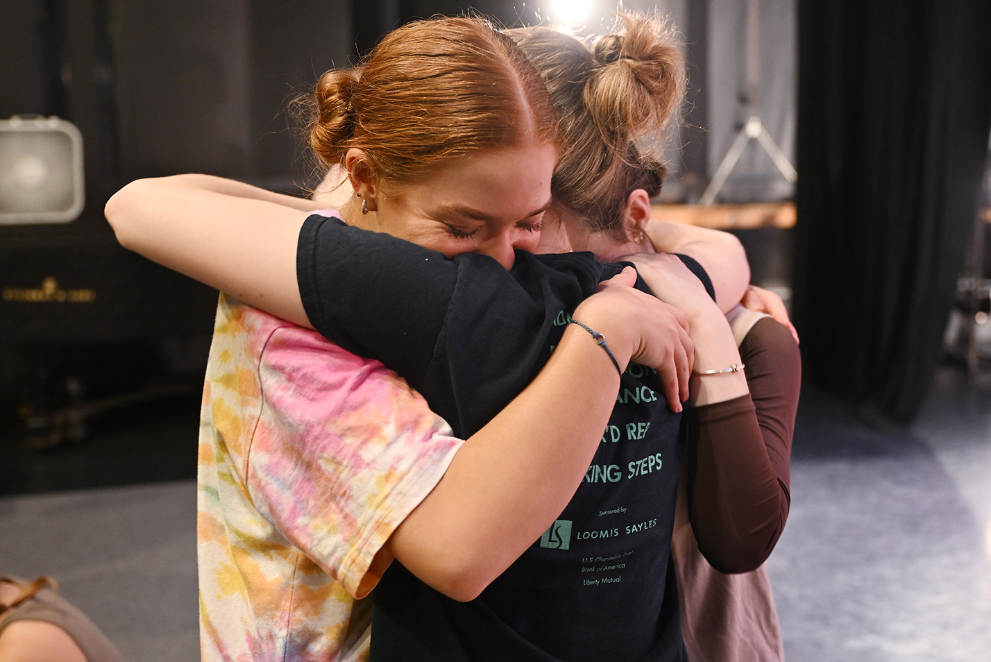 Three dancers embrace after a successful performance.