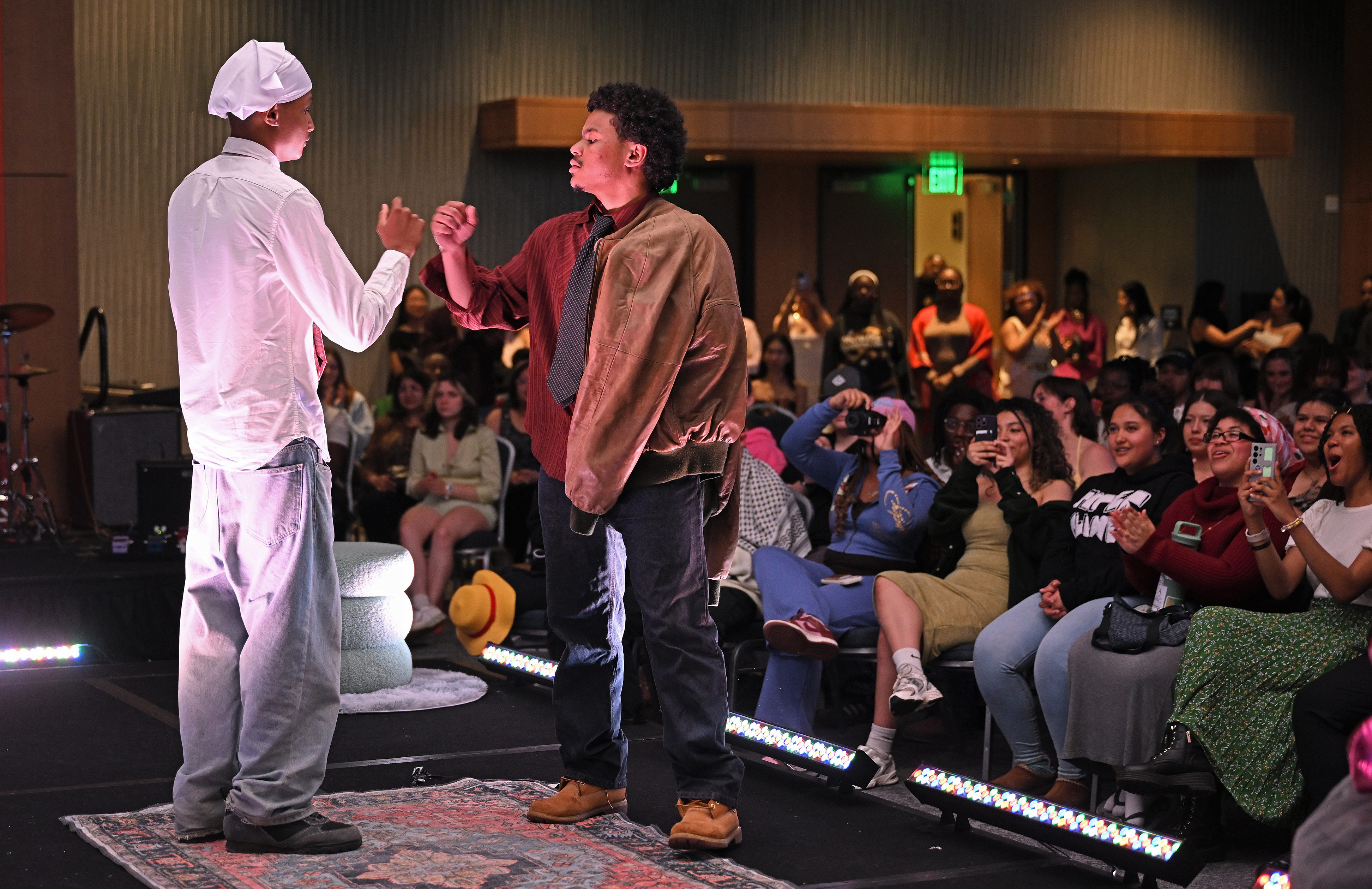 Two student models bump fists to the cheers of their peers.