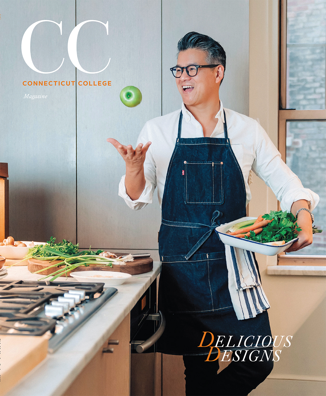 The cover of the Spring 2025 CC Magazine, featuring designer Peter Som '93 tossing a green apple in his kitchen.