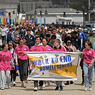 Hundreds of people walk down a New London street as part of the Walk to End Homelessness.