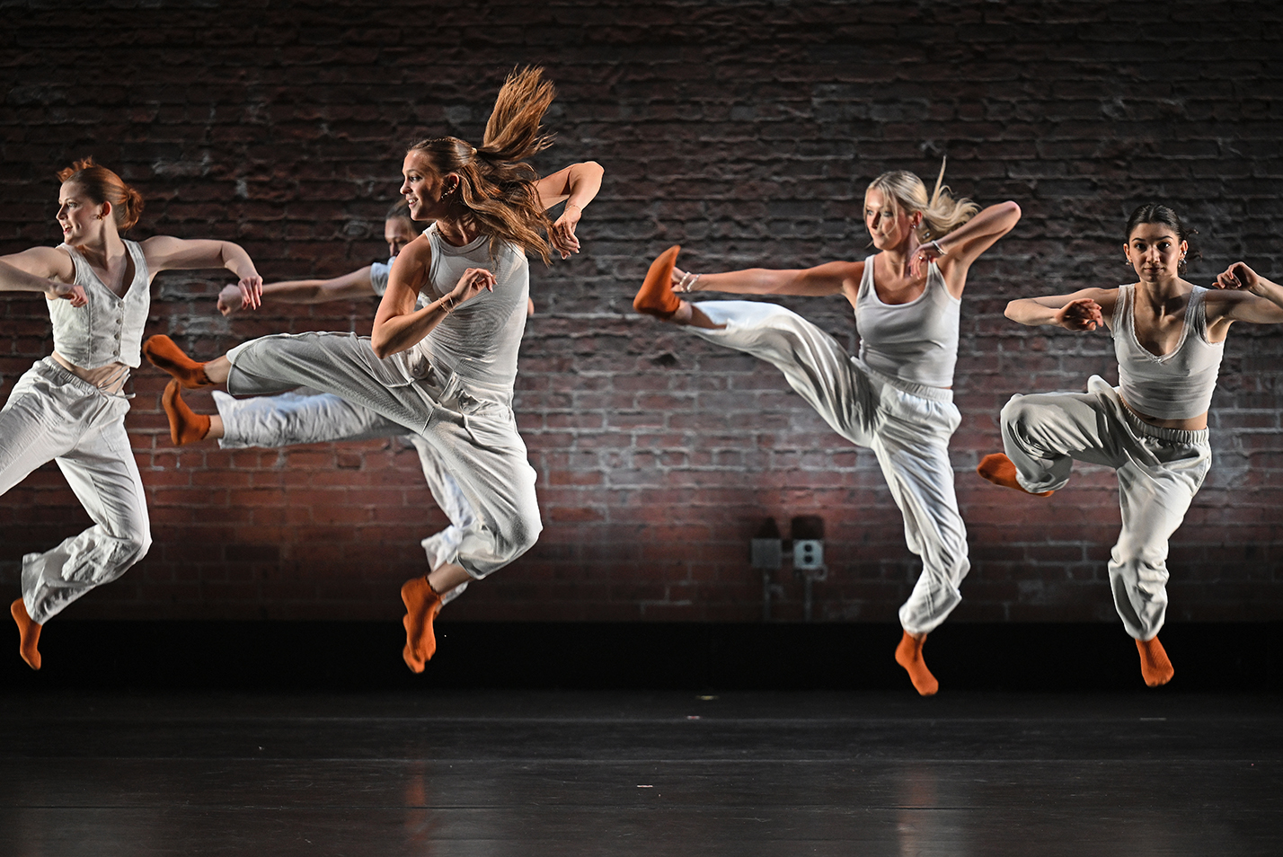 Dancers leap into the air during a modern dance performance.