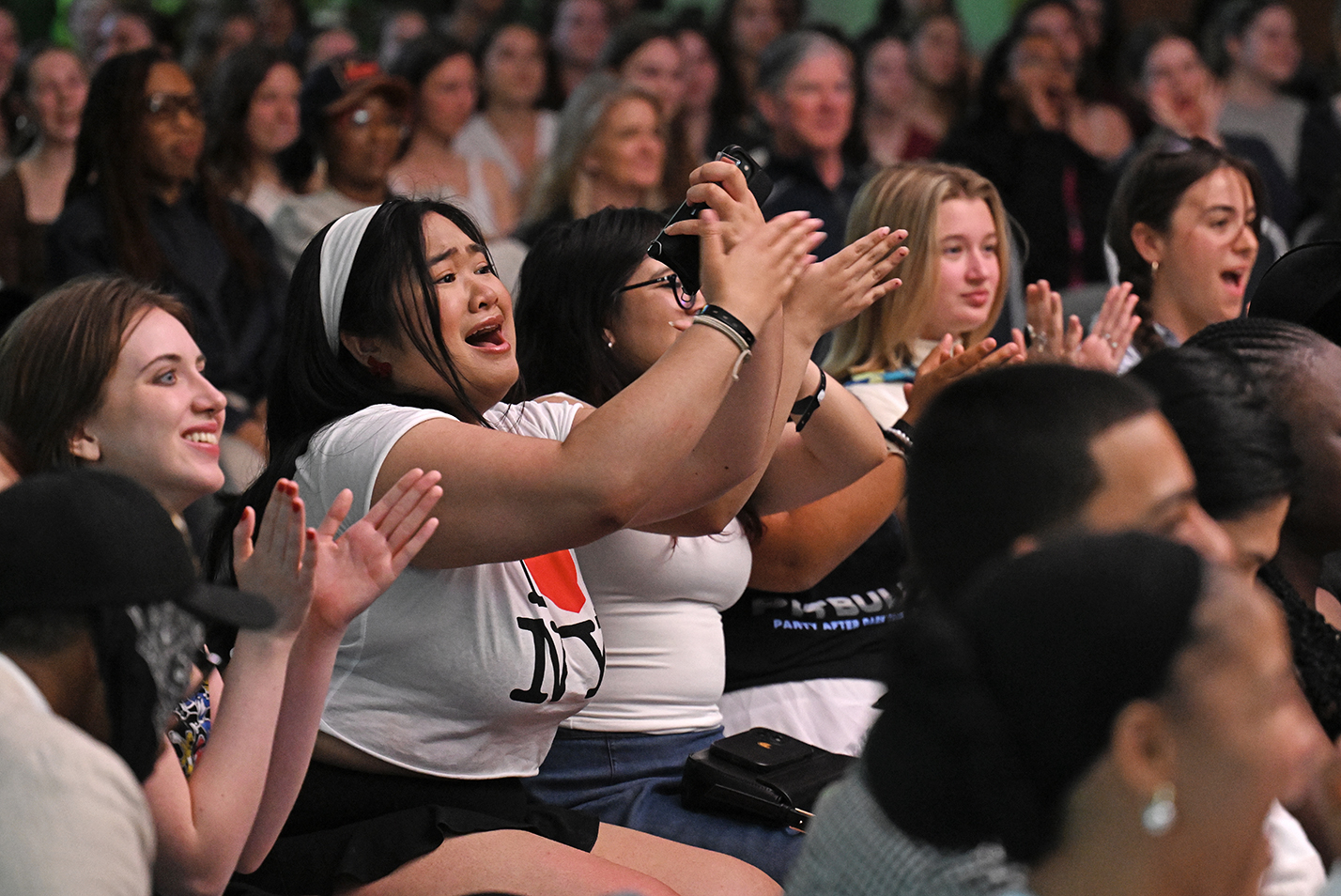 Audience members cheer as student models perform in a fashion show.