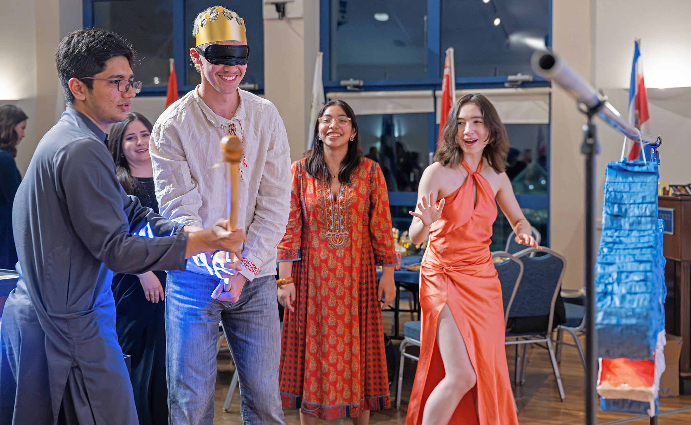 Students, one blindfolded, prepare to take a swing at a Piñata.