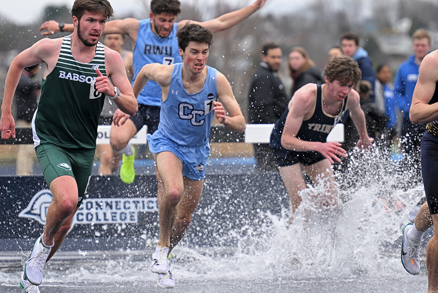 Track athletes splash through the water during the steeplechase race.