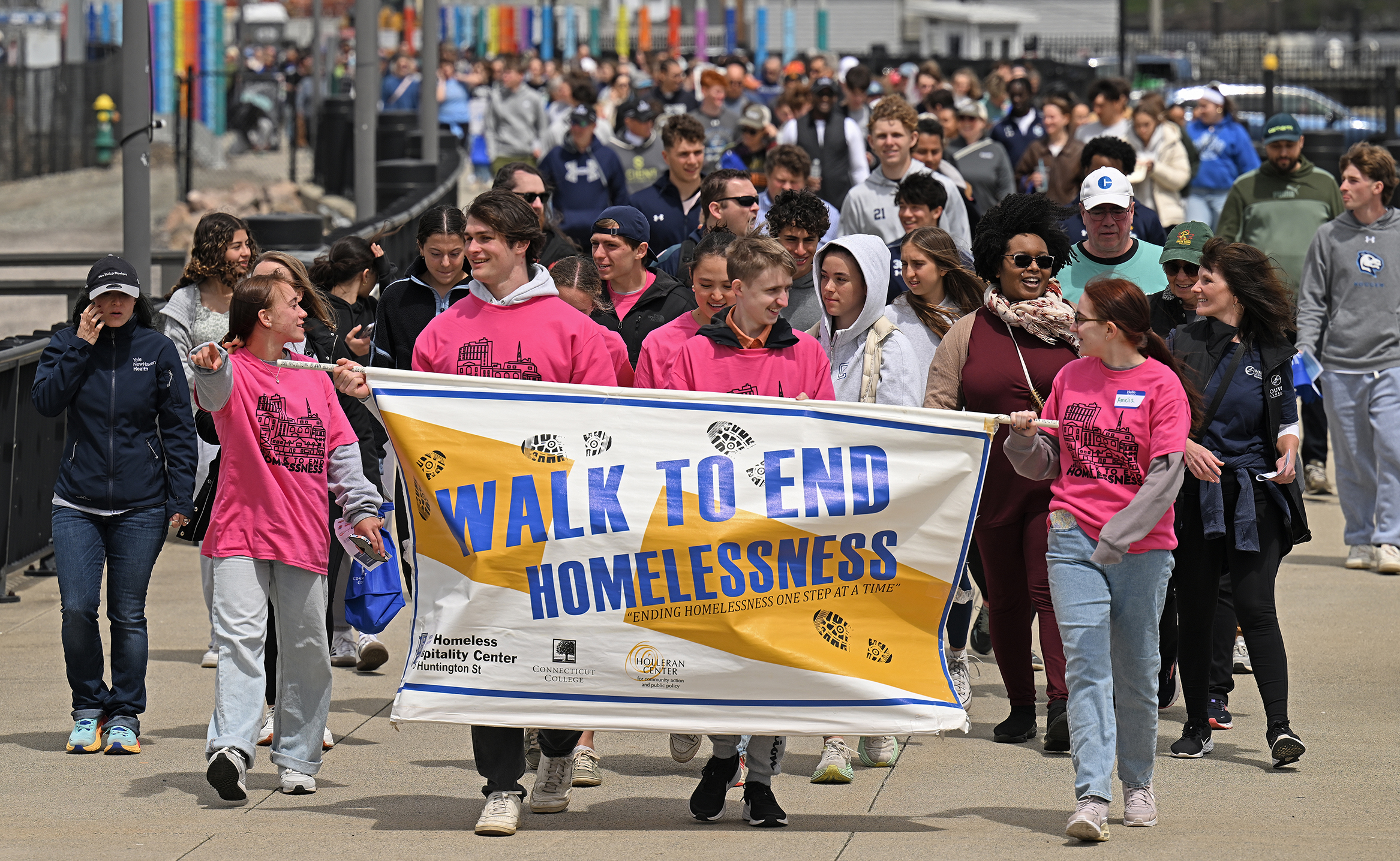 A group of students in pink t-shirts carry a banner and lead a march.