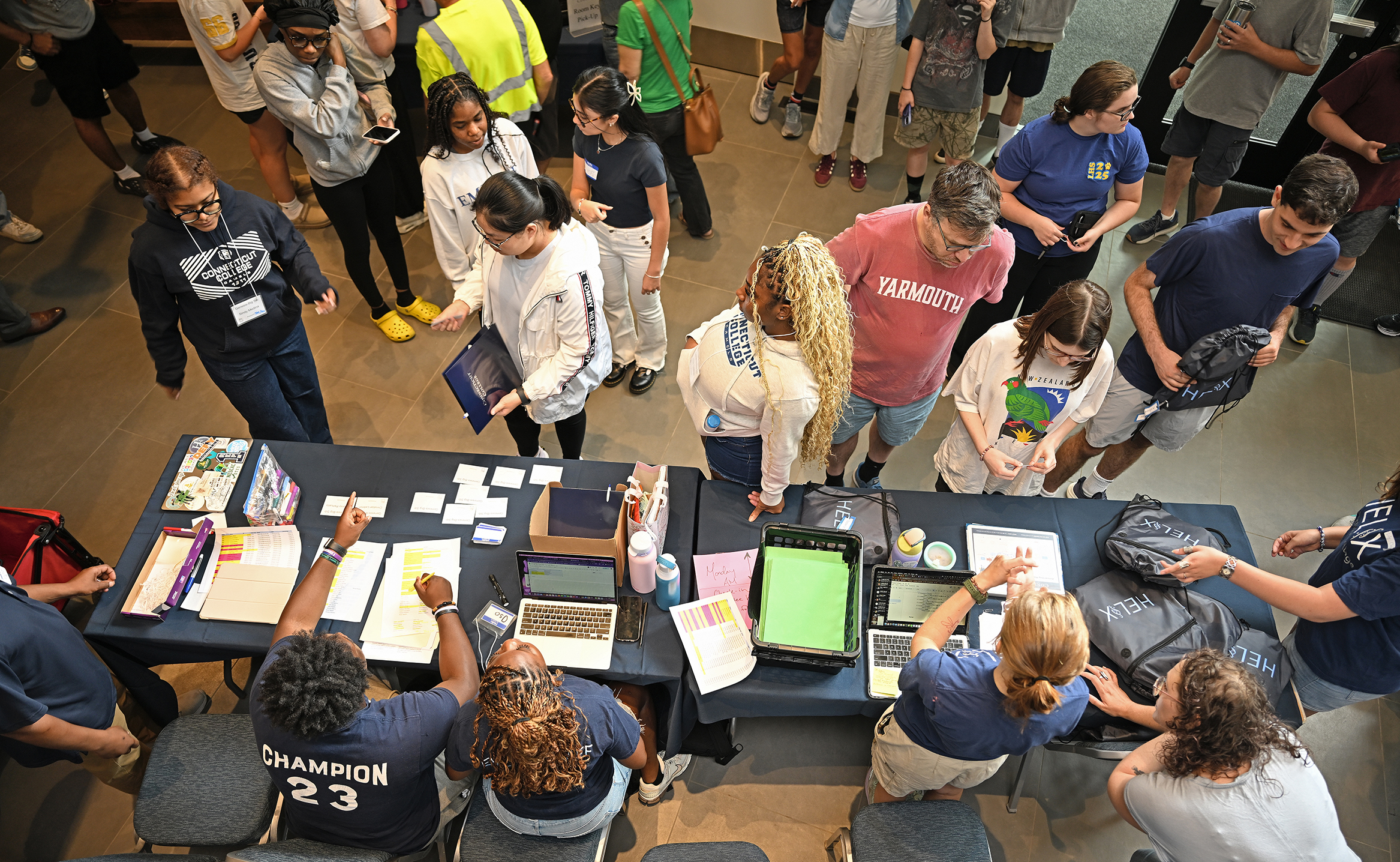 Seen from overhead, college students arriving for their first day check in at tables.