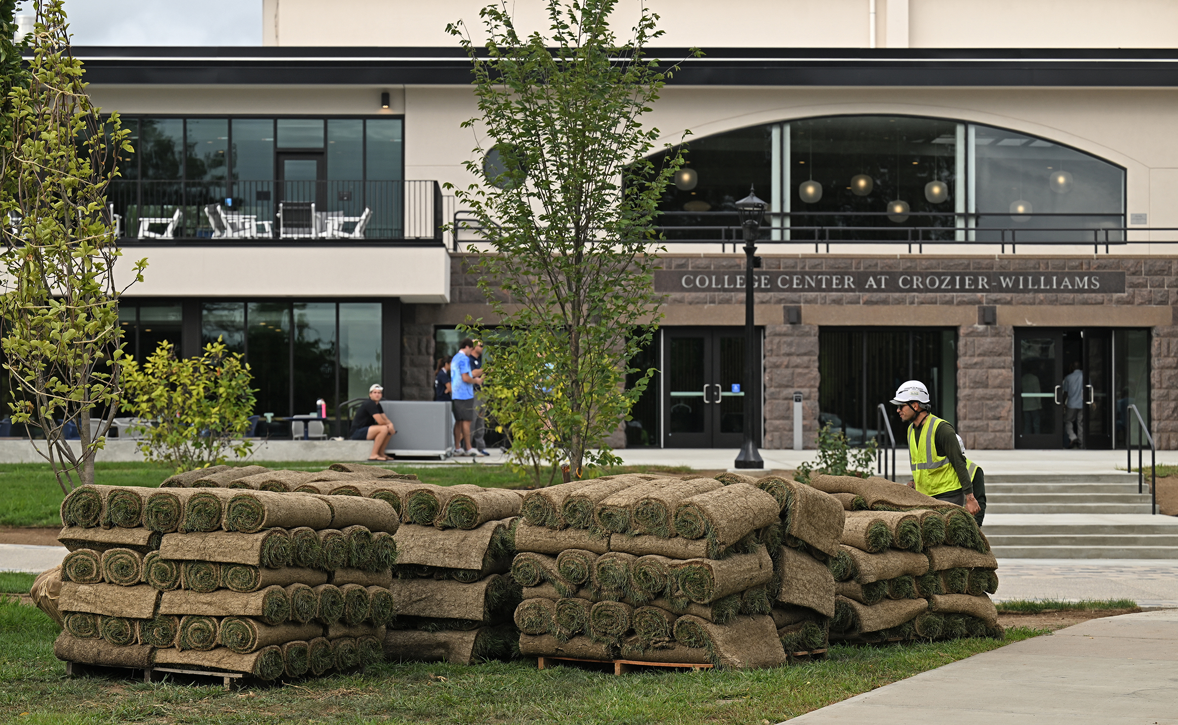 Landscapers prepare to lay new rolls of sod on a college green.