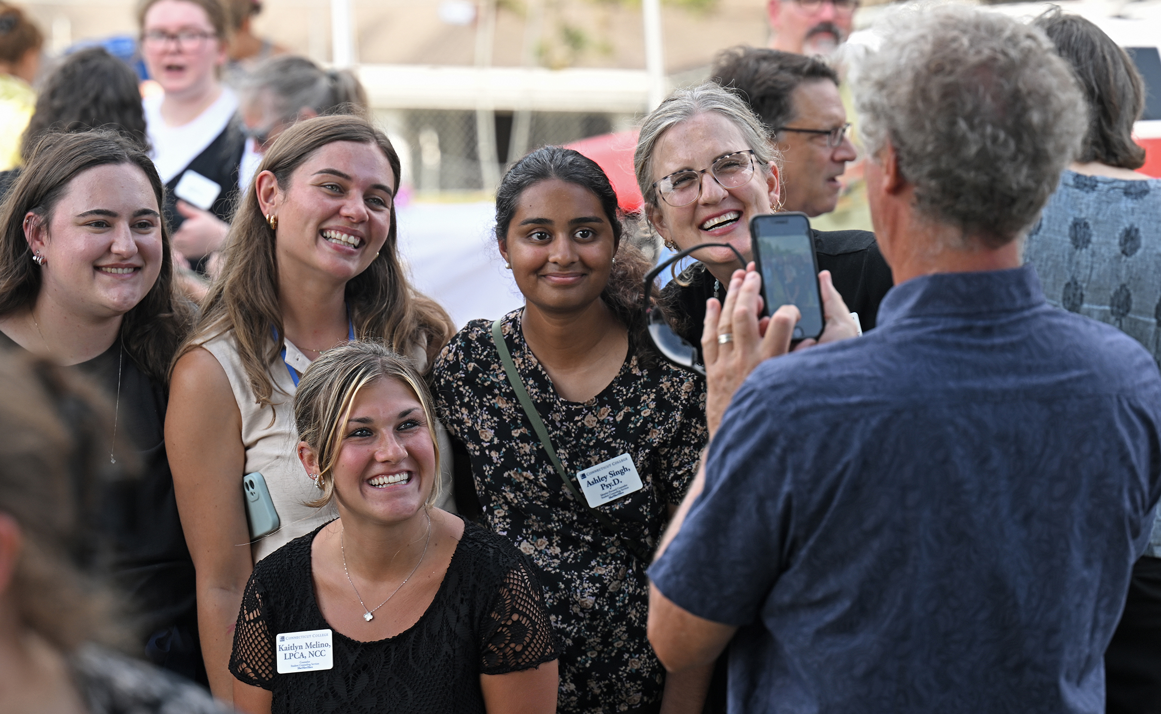A colleague takes a photo of a group of college staffers during a welcome back event on campus.