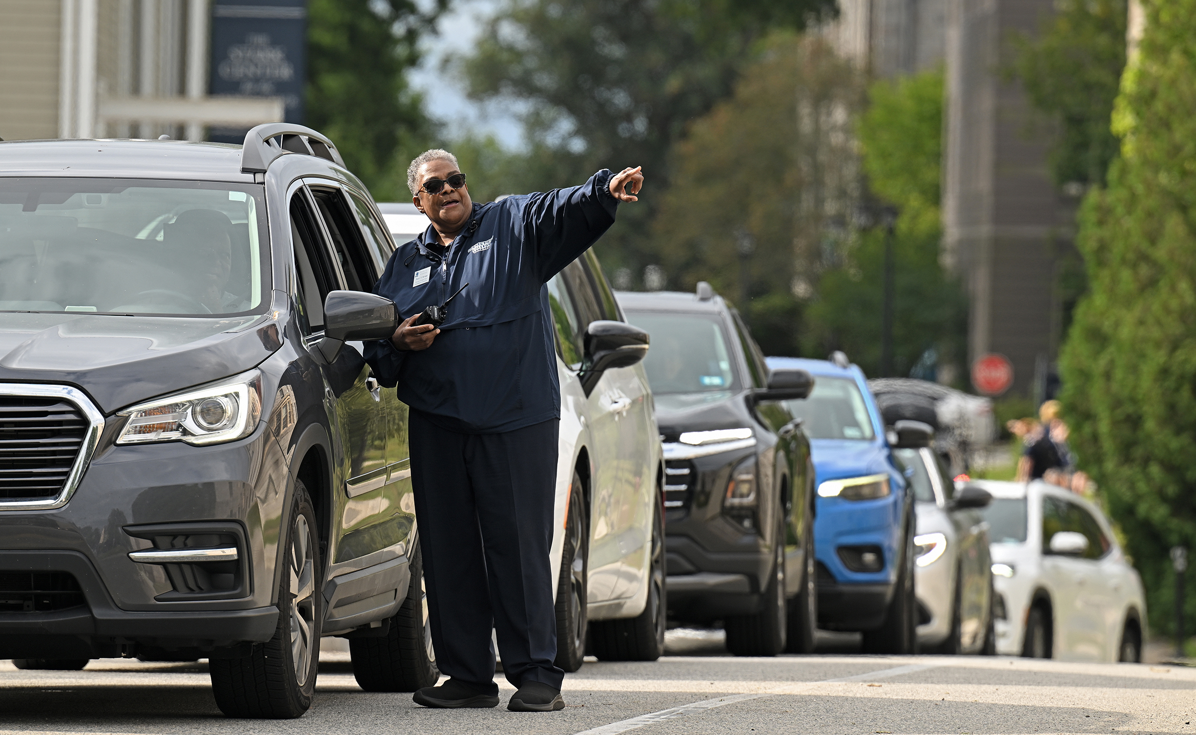 A campus safety officer directs move-in traffic on a roadway.
