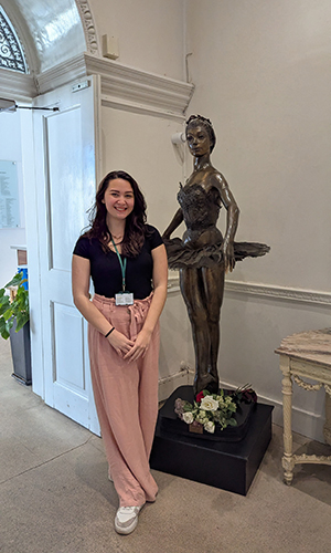 Catja Christensen '23 poses next to a ballerina statue at the Royal Ballet School in London