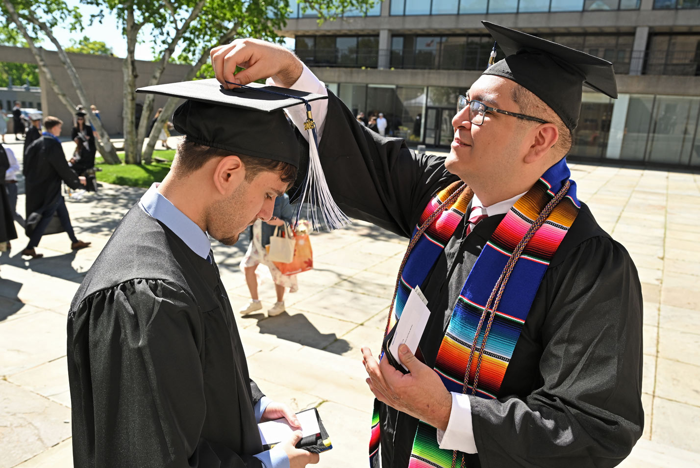 A faculty member checks a cap.