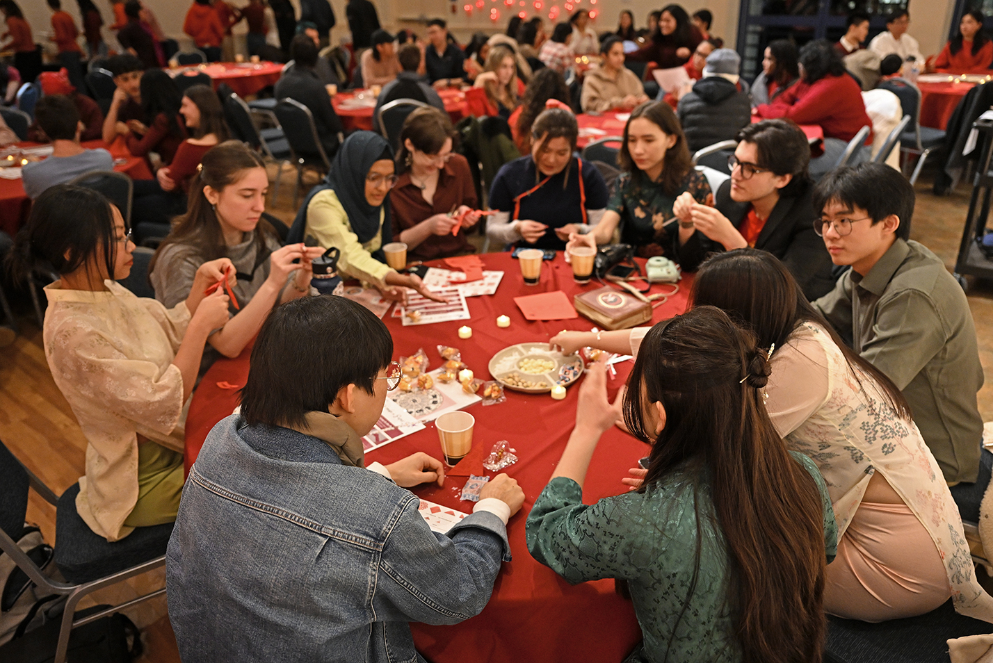 Students gather around large round tables to socialize during a Lunar New Year celebration.