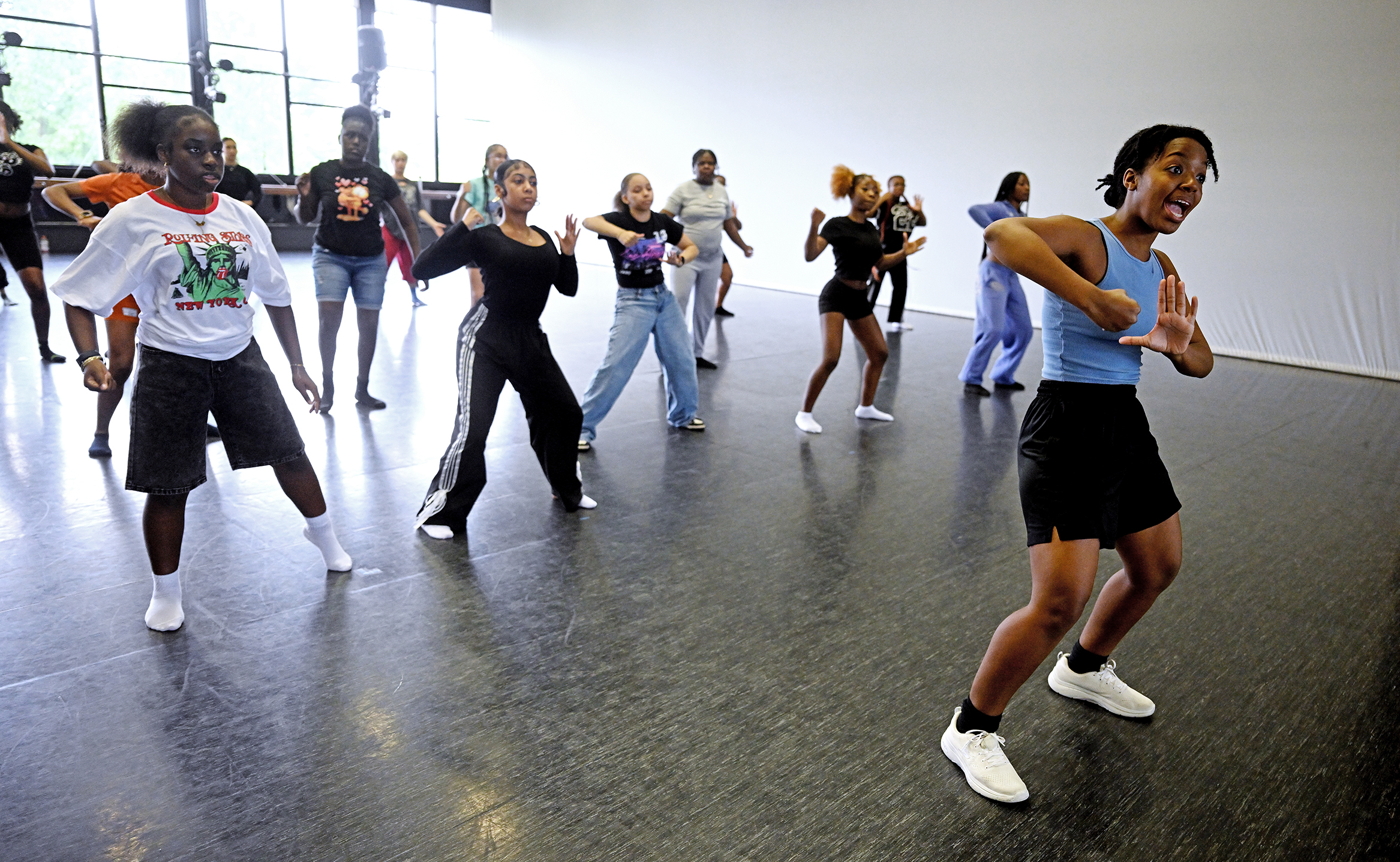 A dance instructor leads a jazz dance class in a large dance studio.