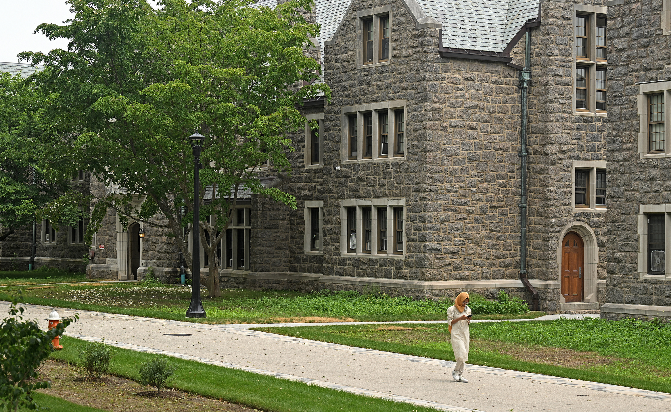 A lone college student walks along a pedestrian promenade.