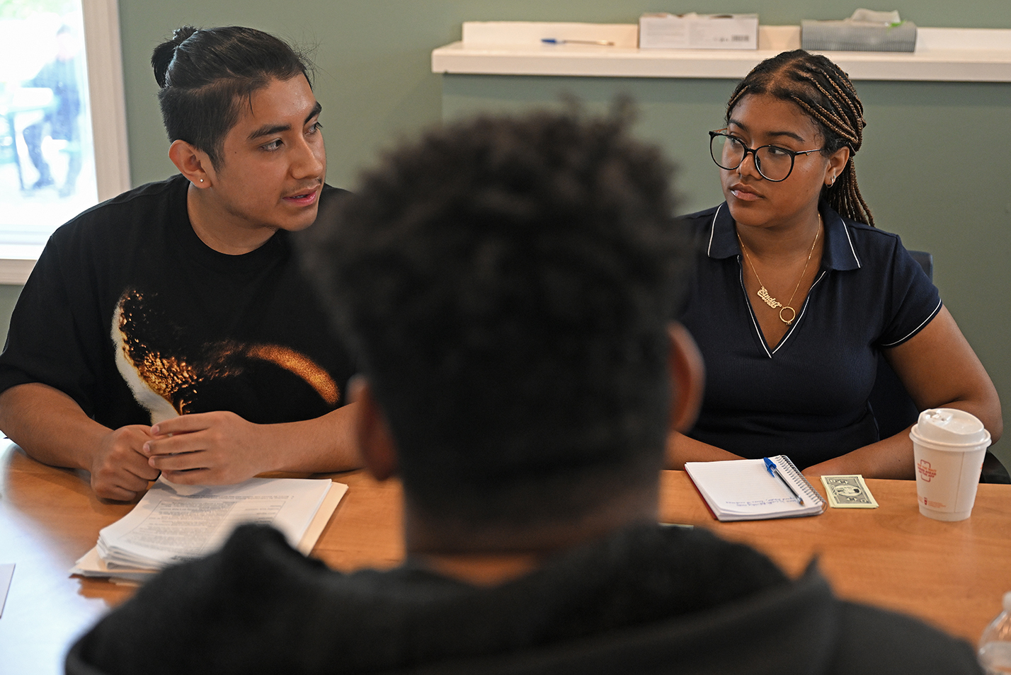 Two students work with a client at a homeless services agency as part of a summer internship.