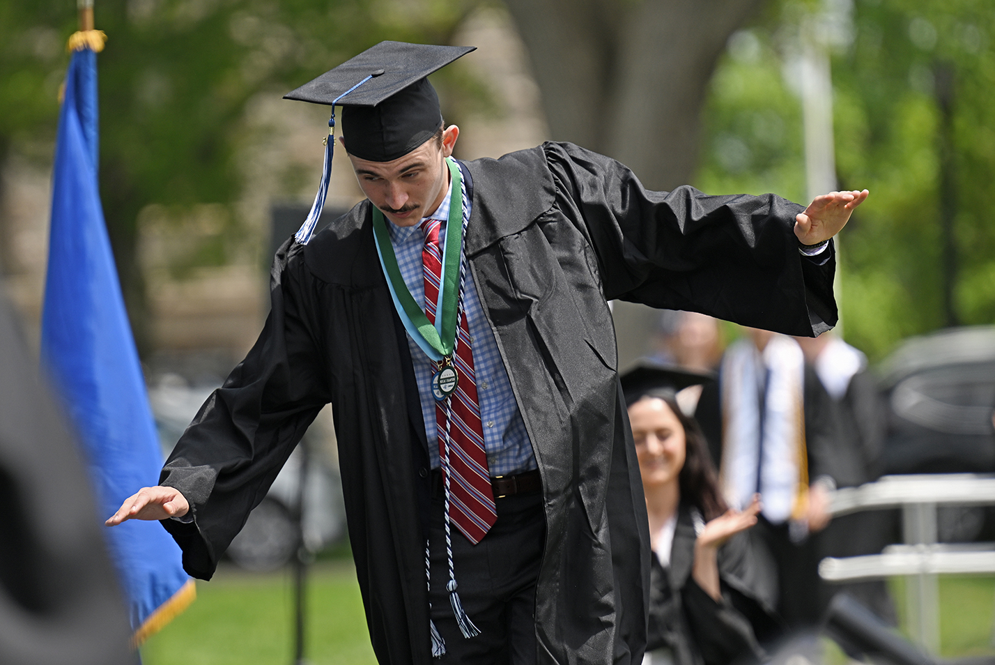 A graduate steadies himself after tripping on the ramp onto the stage to receive his diploma during commencement exercises.