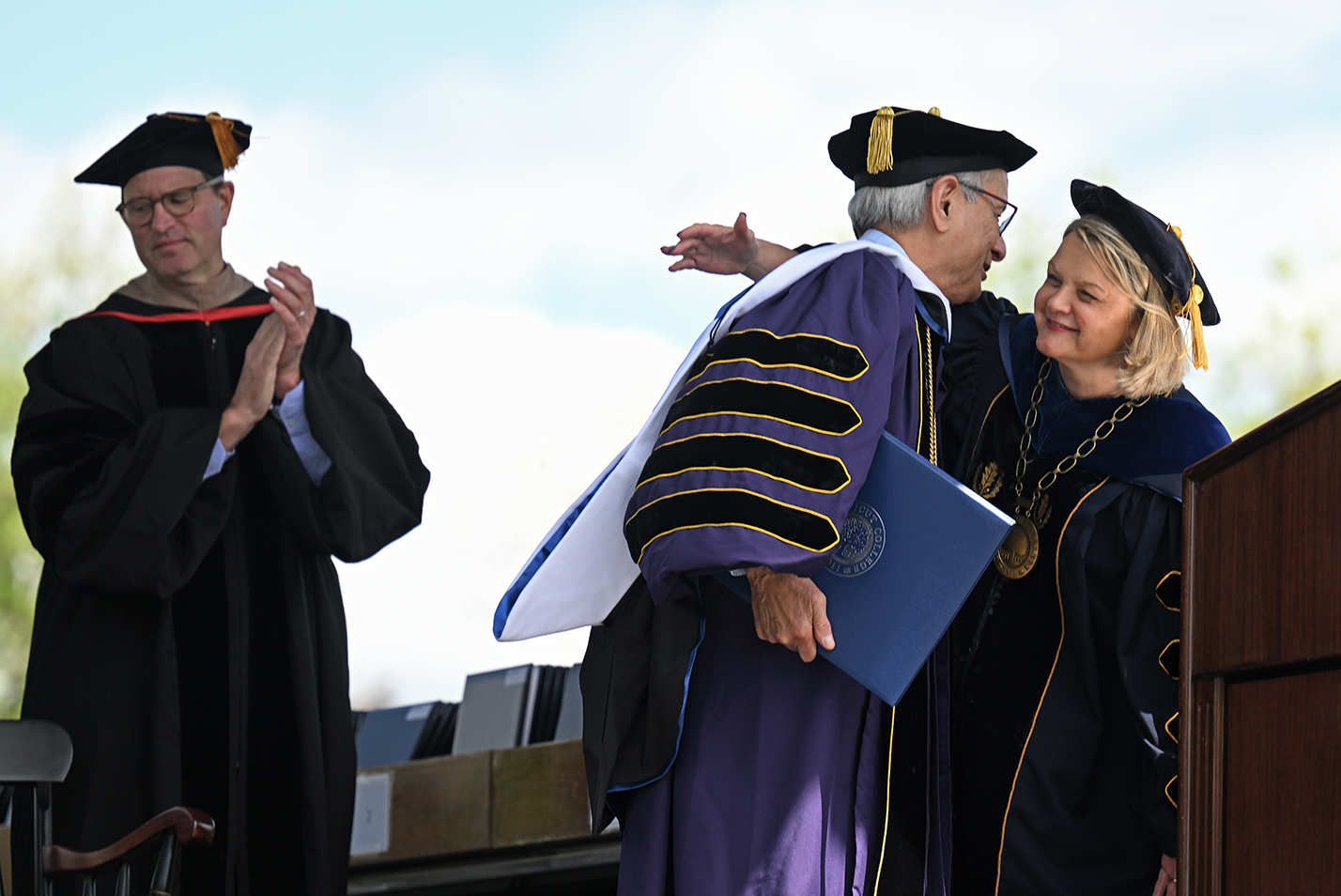The college president embraces the honorary degree recipient on stage during commencement exercises.