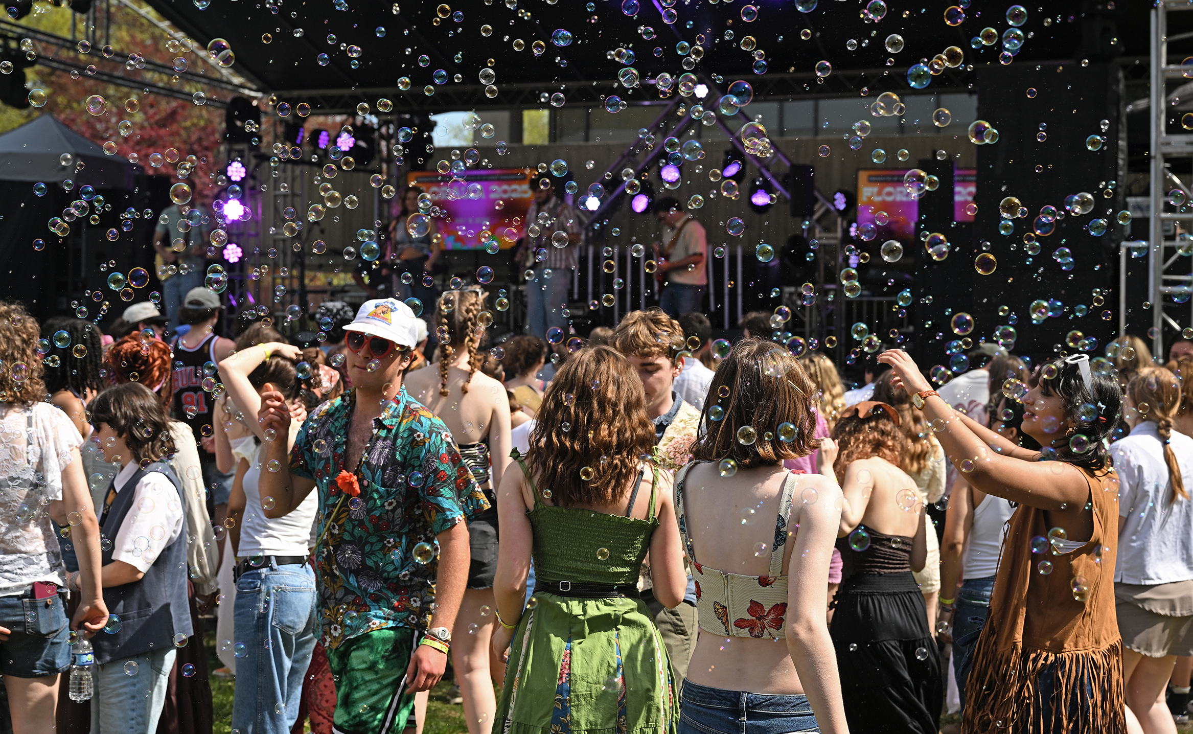 Soap bubbles fill the air as students attend an outdoor music festival.