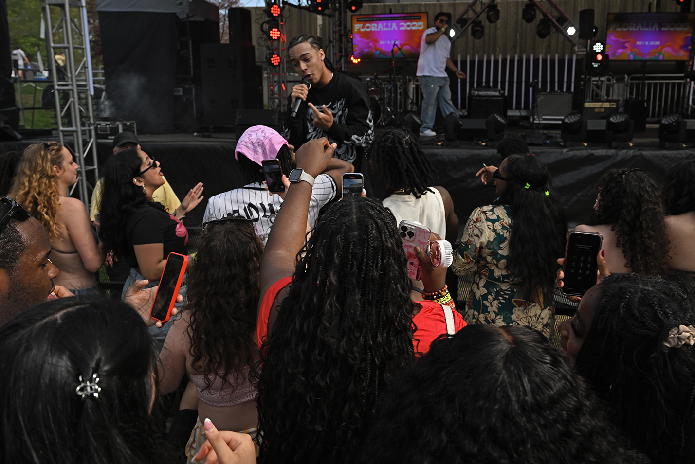A performer moves down to interact with the audience during an outdoor music festival.