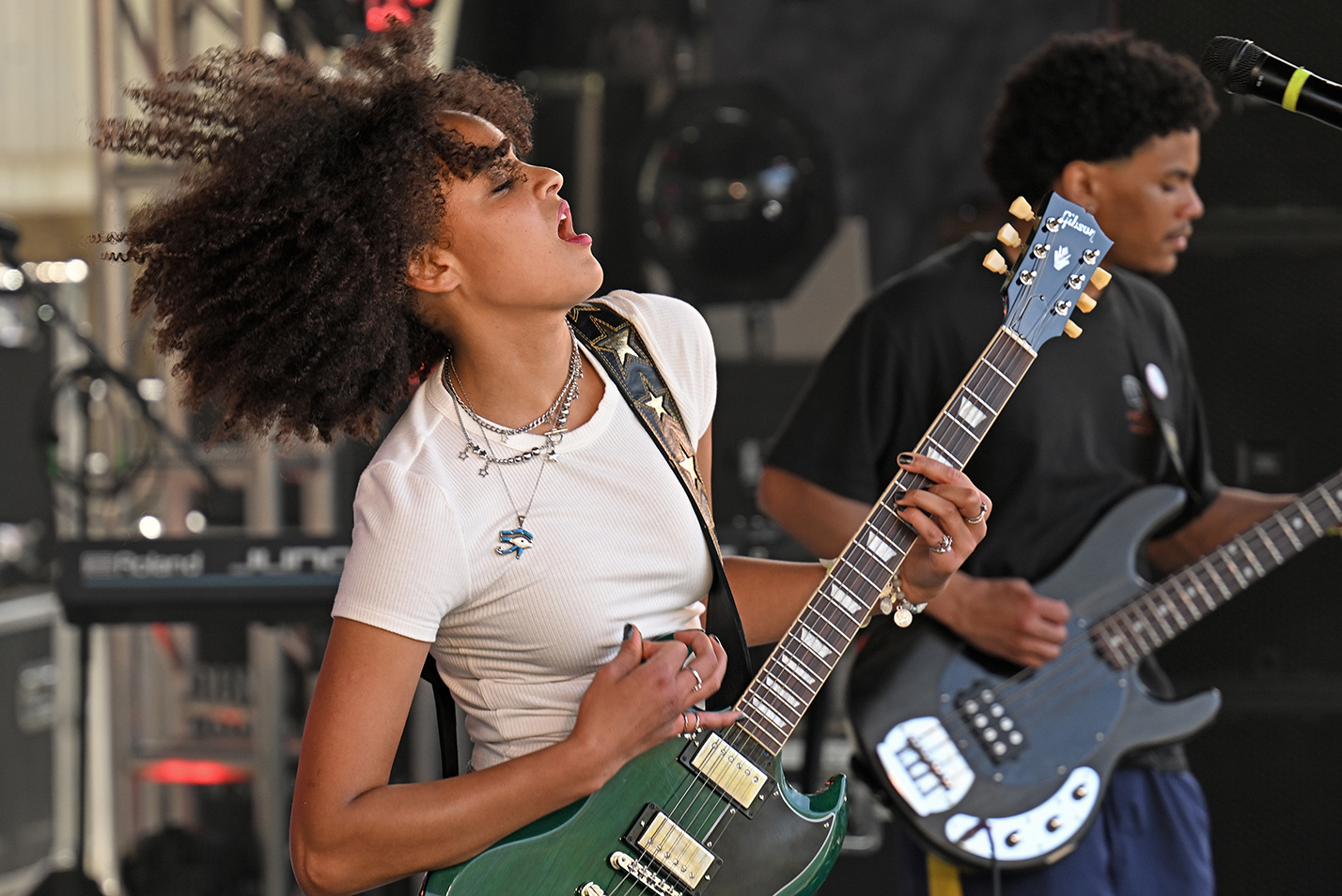 A student guitarist plays on stage during an outdoor music festival.