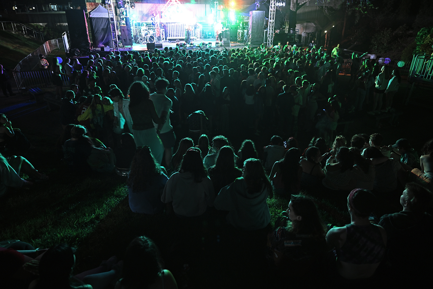 A large crowd of students gather around the stage during a spring outdoor music festival.