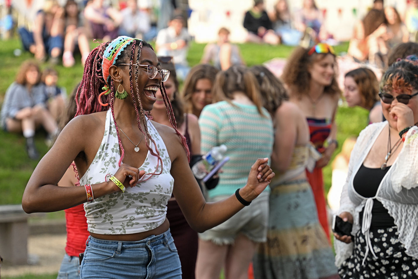 A smiling student dances amongst the crowd during an outdoor music festival.