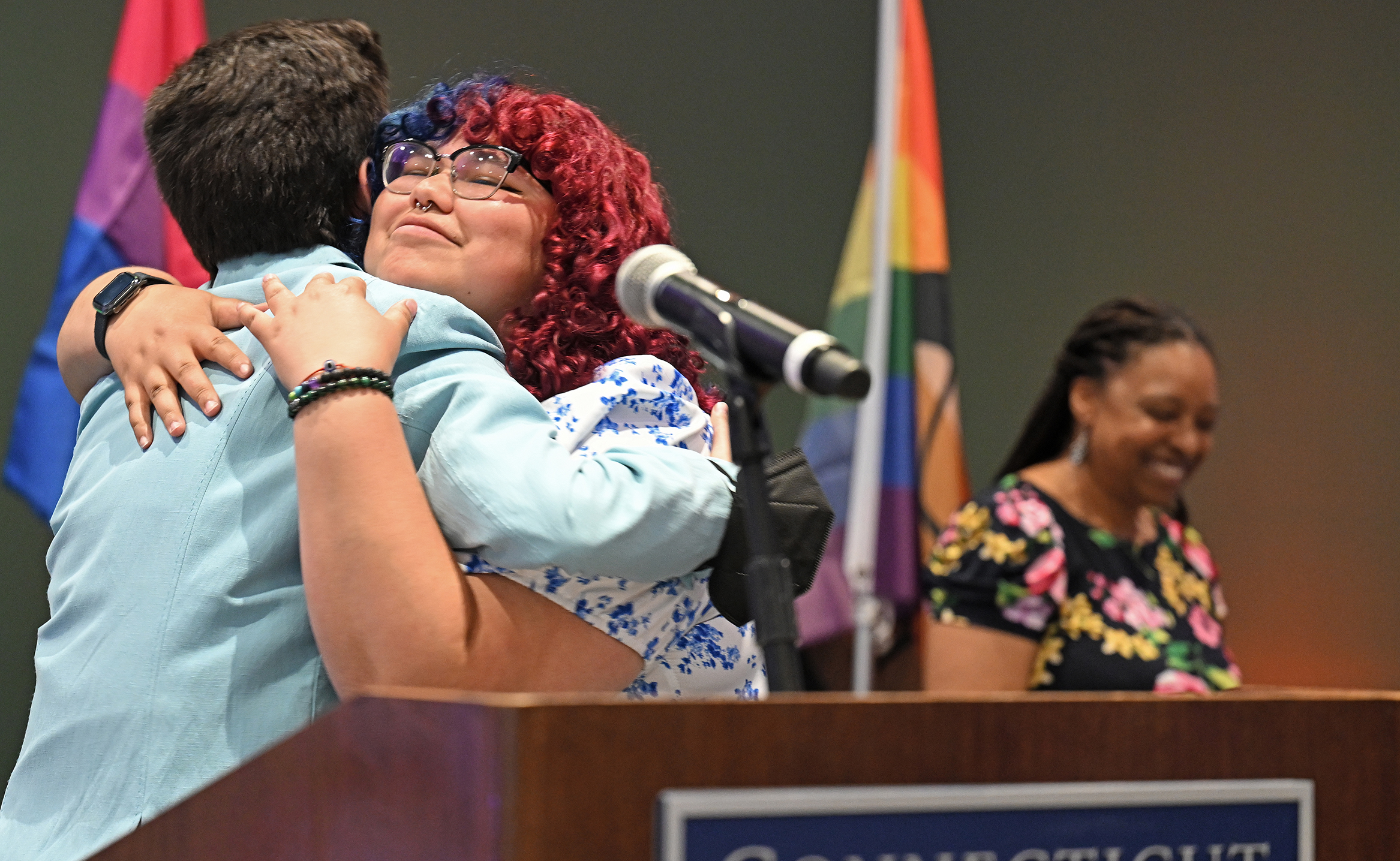 A student with bright red colored hair embraces another during a stolling ceremony.