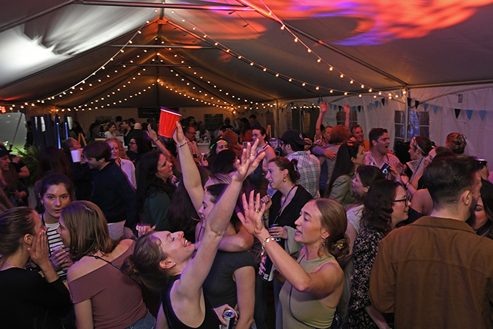College alumni dance under a tent during a reunion event.