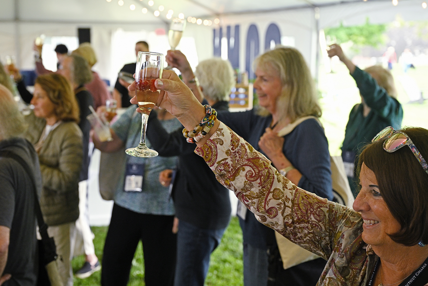 A group of college alumni raise their glasses during a champagne toast at a reunion event.