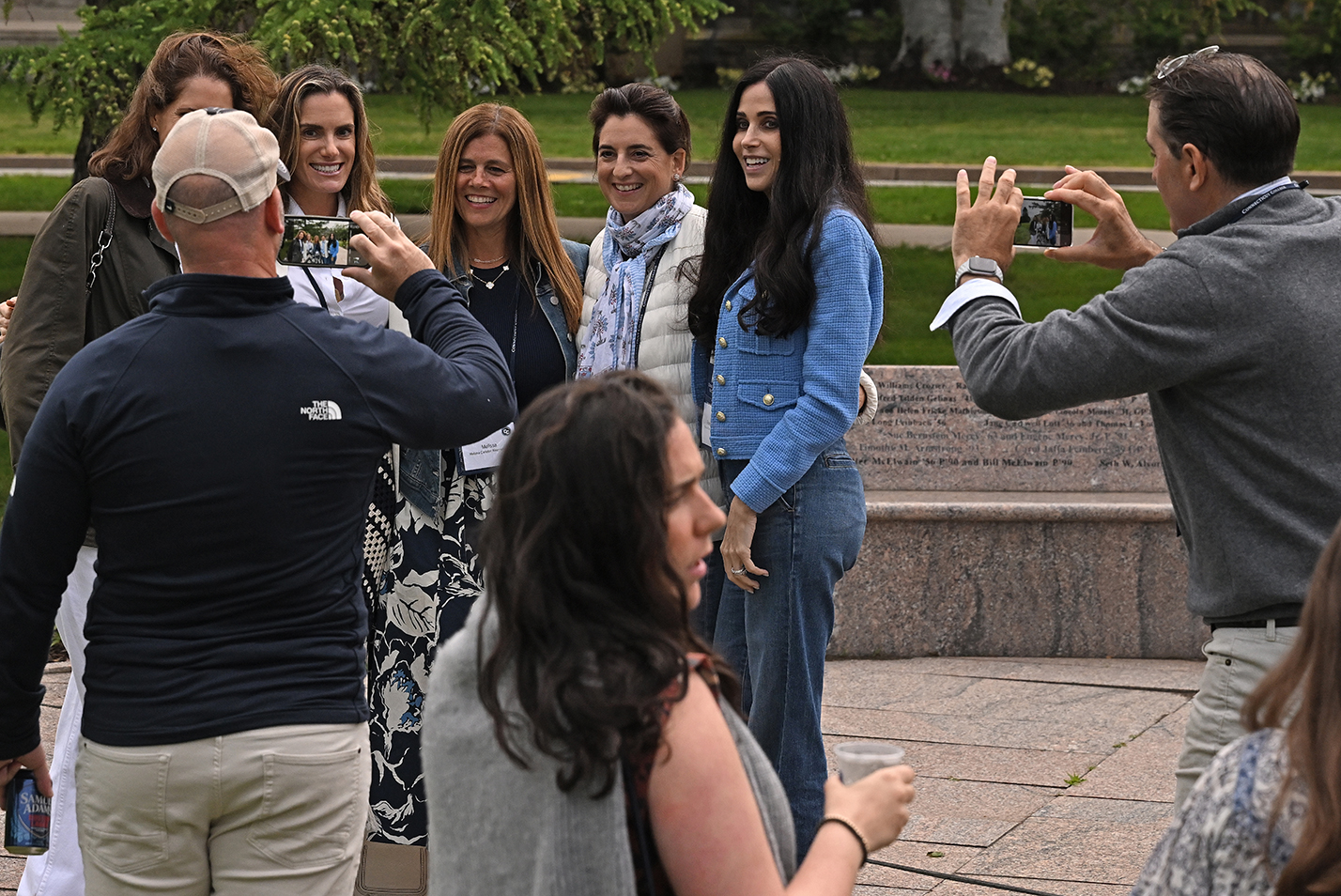 college alumni take photos together on the college green.