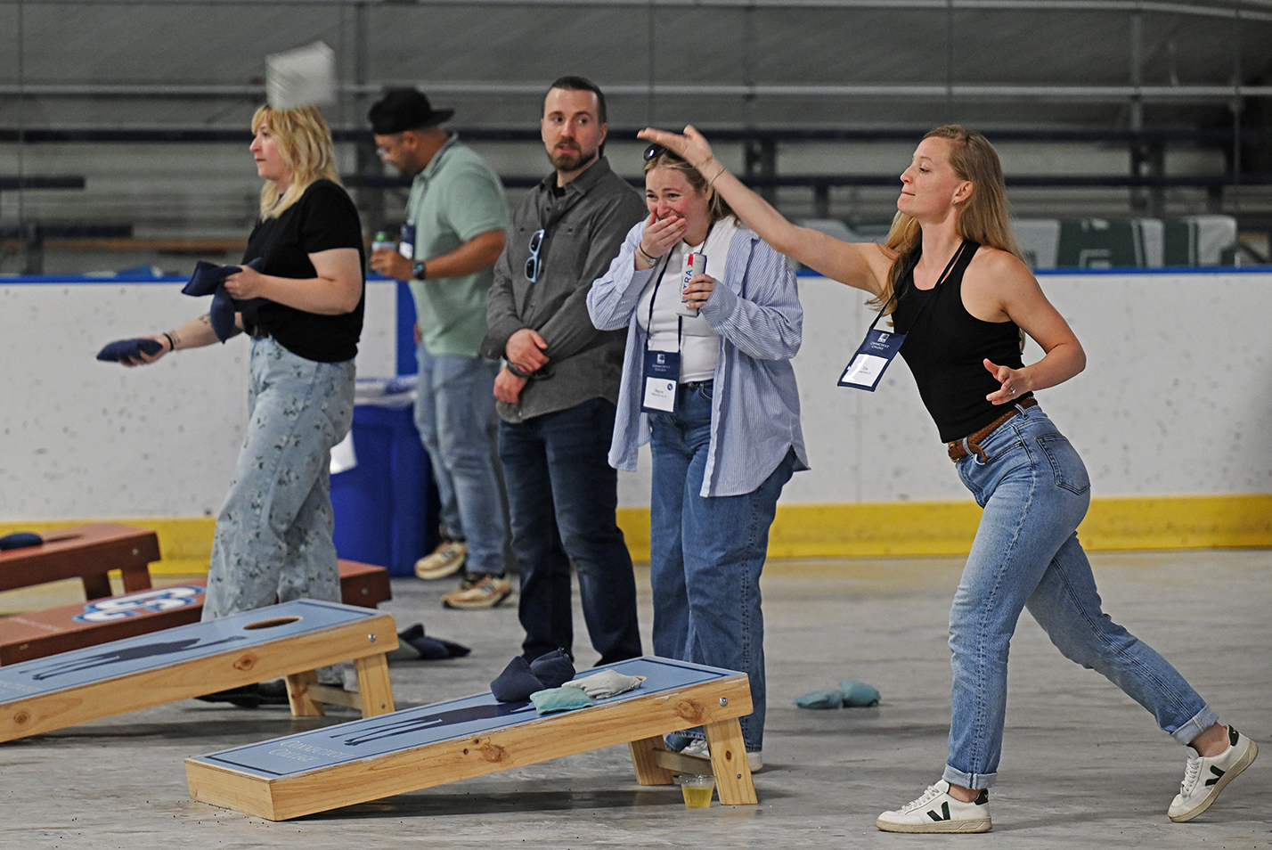 A group of college alumni play games of cornhole.